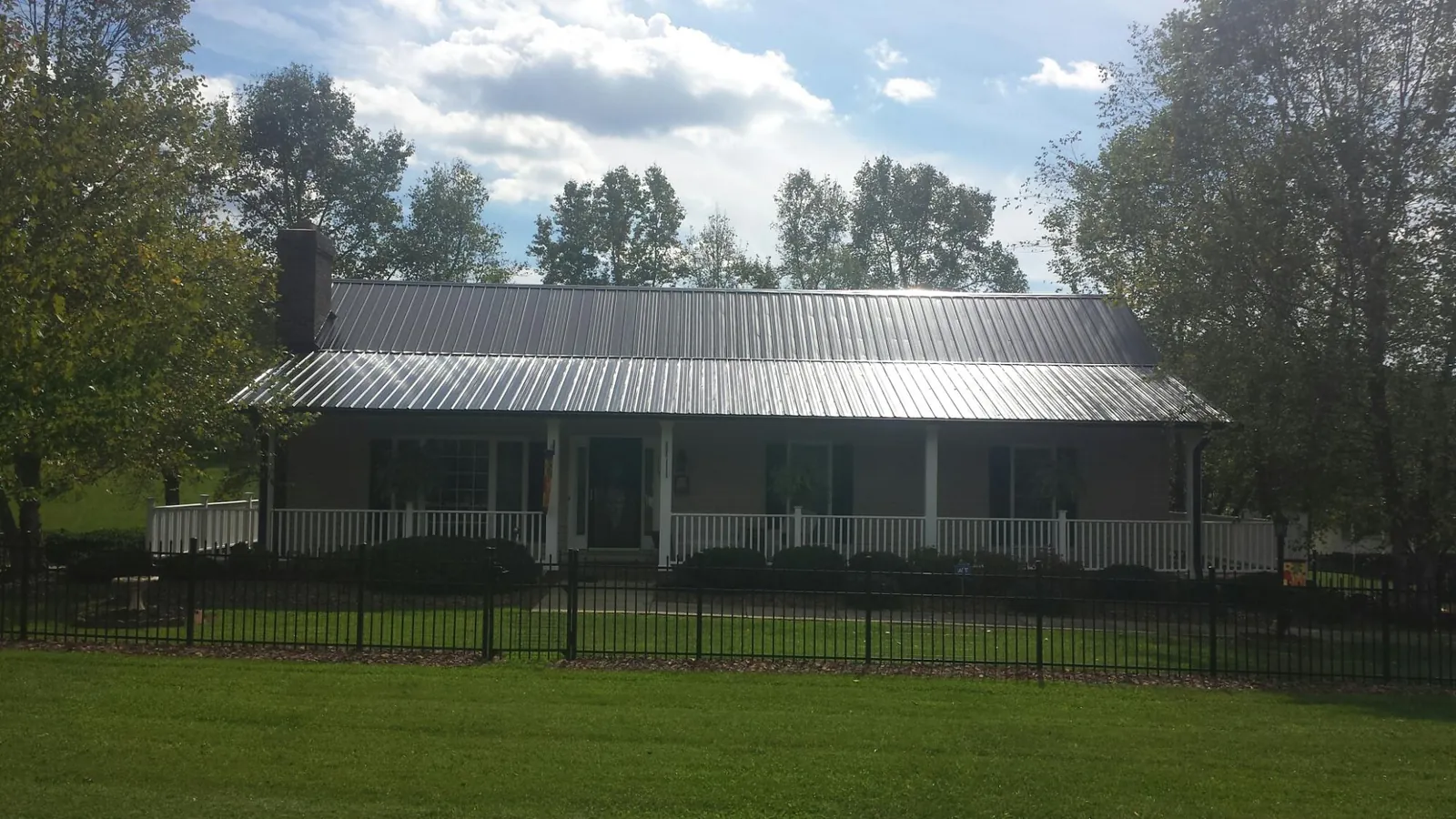 Gray metal roof on a brick ranch with a full width front porch — Gutter Guard Installation work by our crew in Canaan